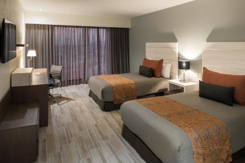 a hotel room with two beds and a desk at Real Inn San Luis Potosi in San Luis Potosí