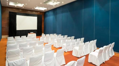 an empty room with white chairs and a screen at Real Inn Guadalajara Expo in Guadalajara
