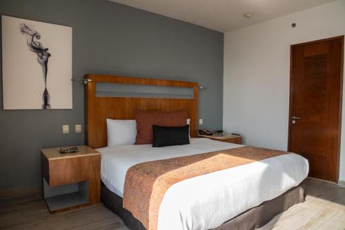 a bedroom with a large bed with a wooden headboard at Real Inn Guadalajara Expo in Guadalajara