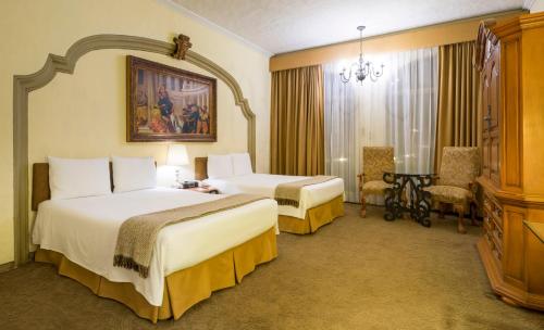 a hotel room with two beds and a chair at Quinta Real Aguascalientes in Aguascalientes