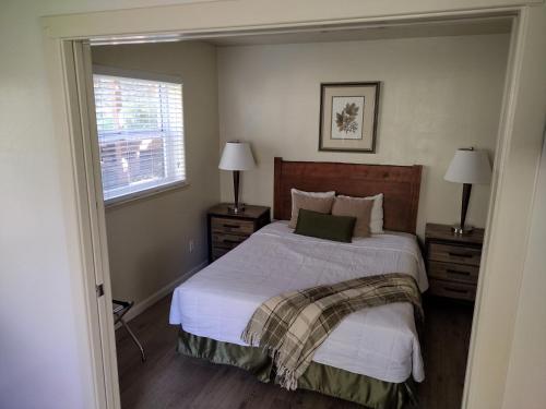 a bedroom with a bed with white sheets and a window at Yosemite Gatekeeper's Lodge in El Portal