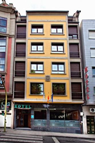 een hoog geel gebouw op de hoek van een straat bij Hotel Herbiña in Cambados