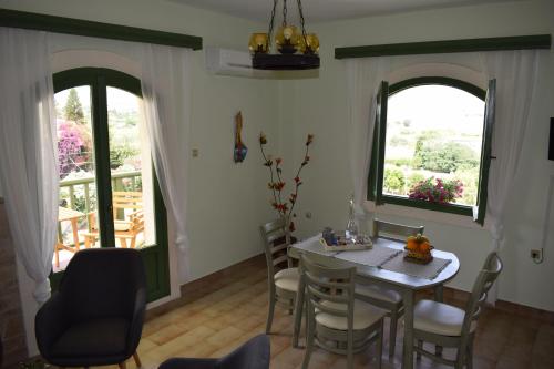 a dining room with a table and chairs and two windows at Bellevue Apartments in Sitia