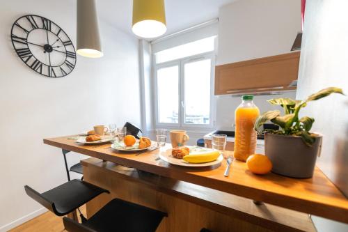 een tafel met borden met voedsel en sinaasappels erop bij KASA AMAZUR - Centre ville & Cosy in Saint-Étienne