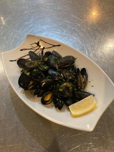 a plate of mussels with a lemon on a table at Hotel Dream in Stara Zagora