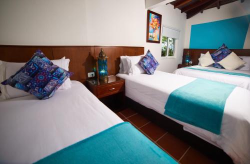 two beds in a room with blue and white at Hotel Mansión Barichara in Barichara