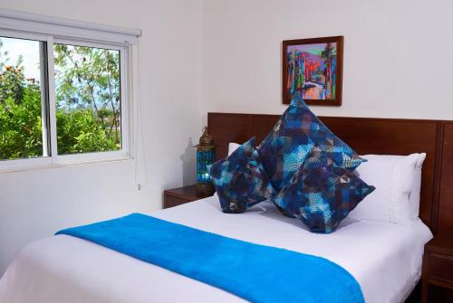 a bed with two blue pillows on top of it at Hotel Mansión Barichara in Barichara