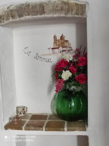 a green vase with flowers sitting on a shelf at La lammia di Pisticci in Pisticci