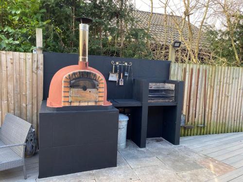 a black outdoor grill with a wood fired oven at Woodpecker Log Cabin with hot tub, pizza oven bbq entertainment area, lakeside with private fishing peg situated at Tattershall Lakes in Tattershall