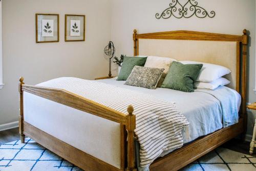 a bedroom with a wooden bed with green and white pillows at Mod Stable House on 10 Acres, Walk to Lake! in Oakwood