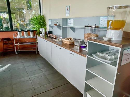 a kitchen with white cabinets and a counter at Tahiti Airport Motel in Faaa