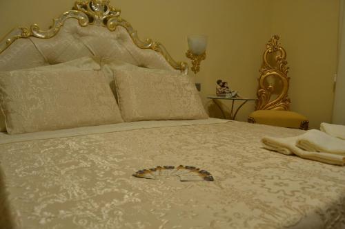 a bed with a white bedspread with a gold frame at Villa D'Anzi B&B in Ginosa
