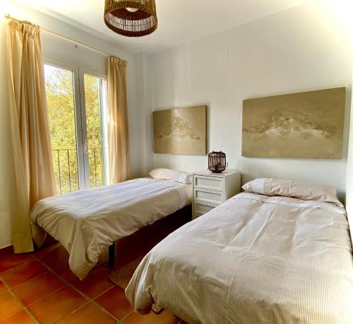 1 dormitorio con 2 camas y ventana en La Almenara, en Aracena