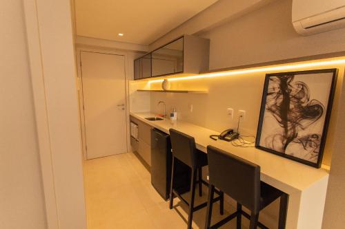 a kitchen with a counter with chairs and a bar at Manaíra Apart Hotel por Carpediem in Tambaú