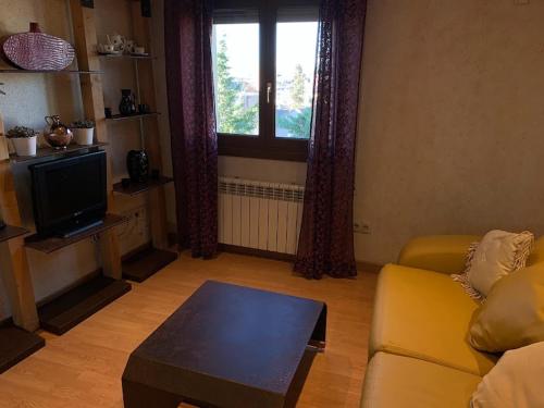 a living room with a yellow couch and a tv at El Rinconcillo - centro histórico de Toledo in Toledo