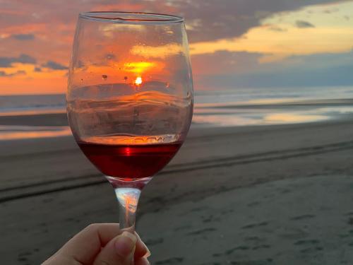 a person holding a glass of wine at the beach at Miguel Surf Camp in Quepos