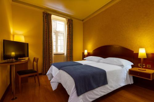 a bedroom with a large bed and a television at Hotel Internacional Porto in Porto