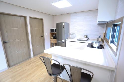 a kitchen with two chairs and a counter and a refrigerator at Jeju Time in Jeju