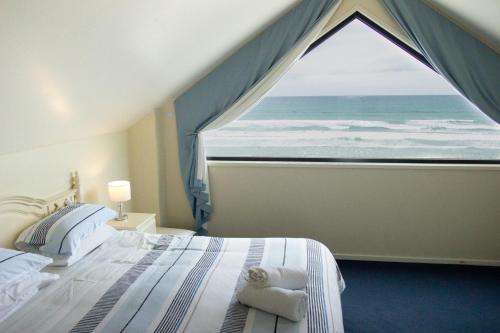 a bedroom with a large window overlooking the ocean at Boathouse Holiday House in Port Fairy