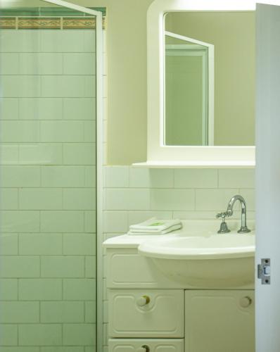 a white bathroom with a sink and a mirror at Boathouse Holiday House in Port Fairy