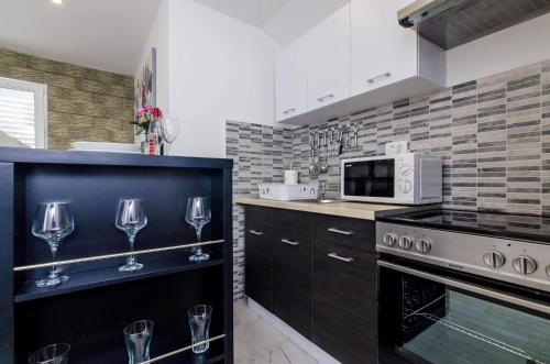 cocina con fogones y copas de vino en Apartments Monica, en Dubrovnik