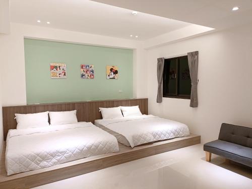 a bedroom with two beds and a chair at Penghu Michi Homestay in Hsing-wen