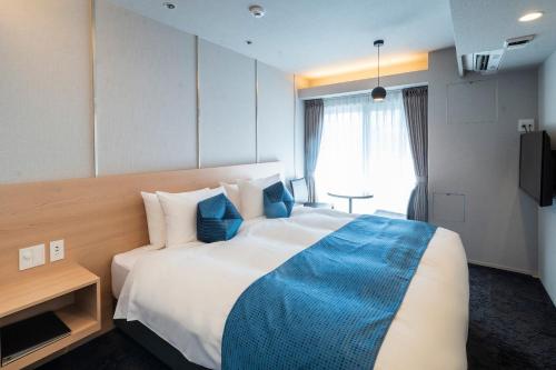 a hotel room with a large bed with a blue blanket at RESI STAY Mayu Grace Hotel in Kyoto