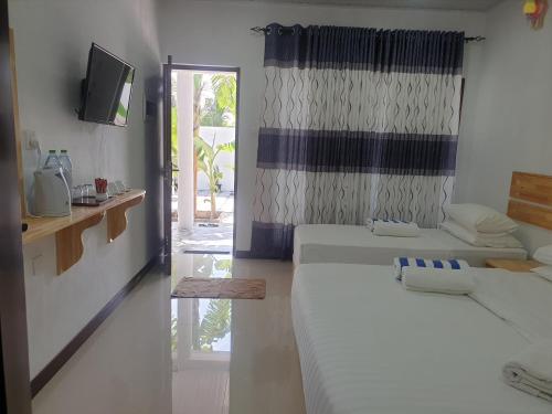 Zimmer mit 2 Betten, einem TV und einem Fenster in der Unterkunft Summer Sky Thoddoo in Thoddoo-Atoll