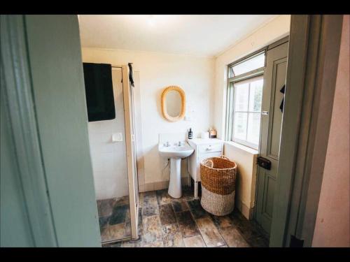 ein Badezimmer mit einem Waschbecken, einem WC und einem Spiegel in der Unterkunft Pooh Corner, Cottage in Robe