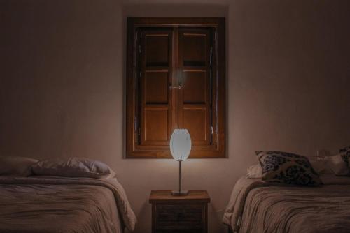 a room with two beds and a lamp on a table at Hotel Posada las Nubes in Parras de la Fuente