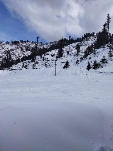 a snow covered slope with a mountain in the background at Orange sky home stay gadaGushaini near jibhi in Jibhi