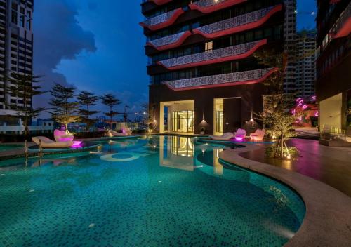 a swimming pool in front of a building at night at LIV Signature Arte Plus in Kuala Lumpur