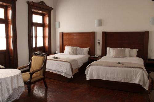 a hotel room with two beds and a chair at El Serafin Hotel Boutique in Querétaro