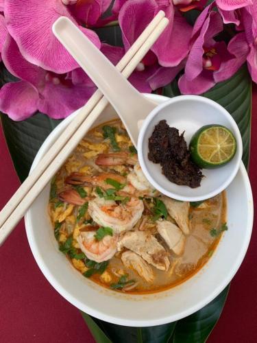 a bowl of seafood soup with chopsticks and a bowl of shrimp at Telang Usan Hotel Kuching in Kuching
