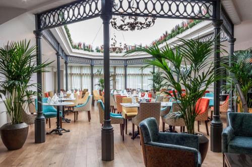 a restaurant with tables and chairs and plants at Gonville Hotel in Cambridge