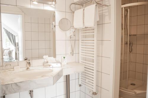 a white bathroom with a sink and a mirror at Hotel & Restaurant Am Alten Rhin in Neuruppin