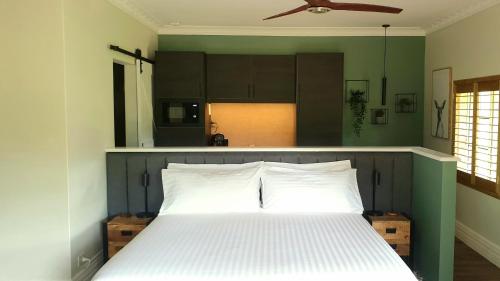 um quarto com uma cama branca com paredes verdes e um tecto em Blackwood Valley Suites em Balingup