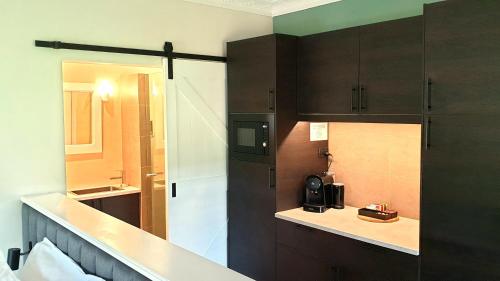 a kitchen with dark brown cabinets and a sink at Blackwood Valley Suites in Balingup