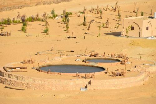 two pools of water in the middle of a desert at Hayaat siwa hot spring in Siwa