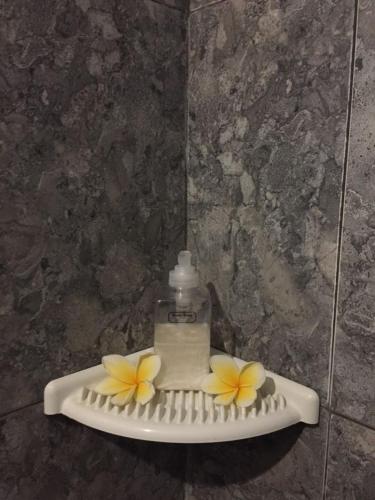 a bottle of soap and flowers on a hair brush at Pondok Mangga in Mataram