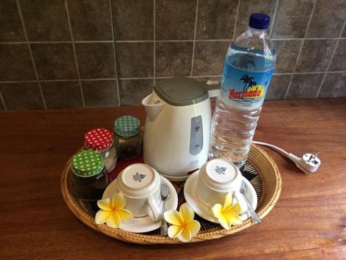a plate with a bottle of water and a tea set with flowers at Pondok Mangga in Mataram