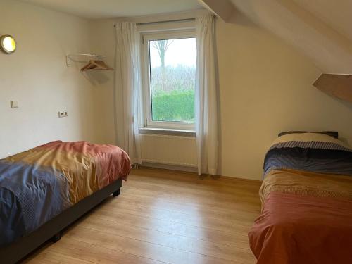 sypialnia z 2 łóżkami i oknem w obiekcie Vakantiewoning Op De Bos w mieście Roggel