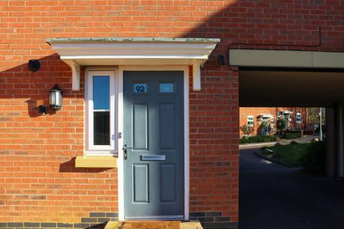a blue door on the side of a brick building at Chichele House, sleeps 8, Nr Rushden Lakes, allocated parking, corporate welcome in Higham Ferrers