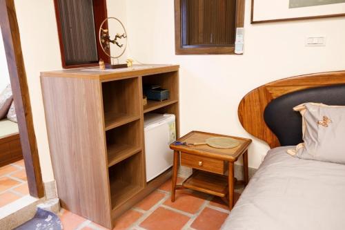 a small room with a bed and a desk next to a bed at 新龍頭古厝行館 Shin Long Tou B&B in Jinning