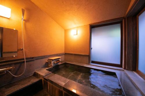 a bathroom with a bath tub with a large window at Yufuin Bettei Itsuki in Yufuin