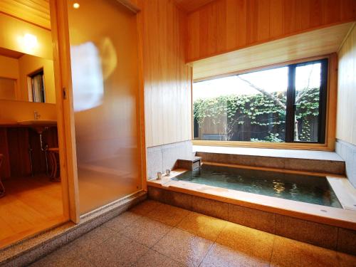 a jacuzzi tub in a room with a window at Toushinan Komeya in Ito