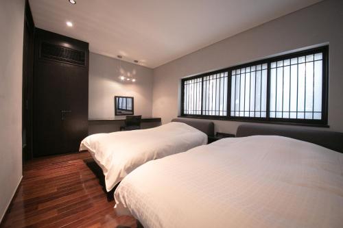 a bedroom with two beds and a window at Yufuin Bettei Itsuki in Yufuin