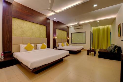 a hotel room with two beds and a flat screen tv at Khanvel Resort in Silvassa
