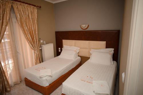 two beds in a small room with a window at Hotel Konti in Korçë