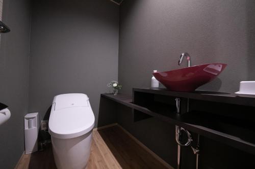 a bathroom with a white toilet and a red sink at Yufuin Bettei Itsuki in Yufuin